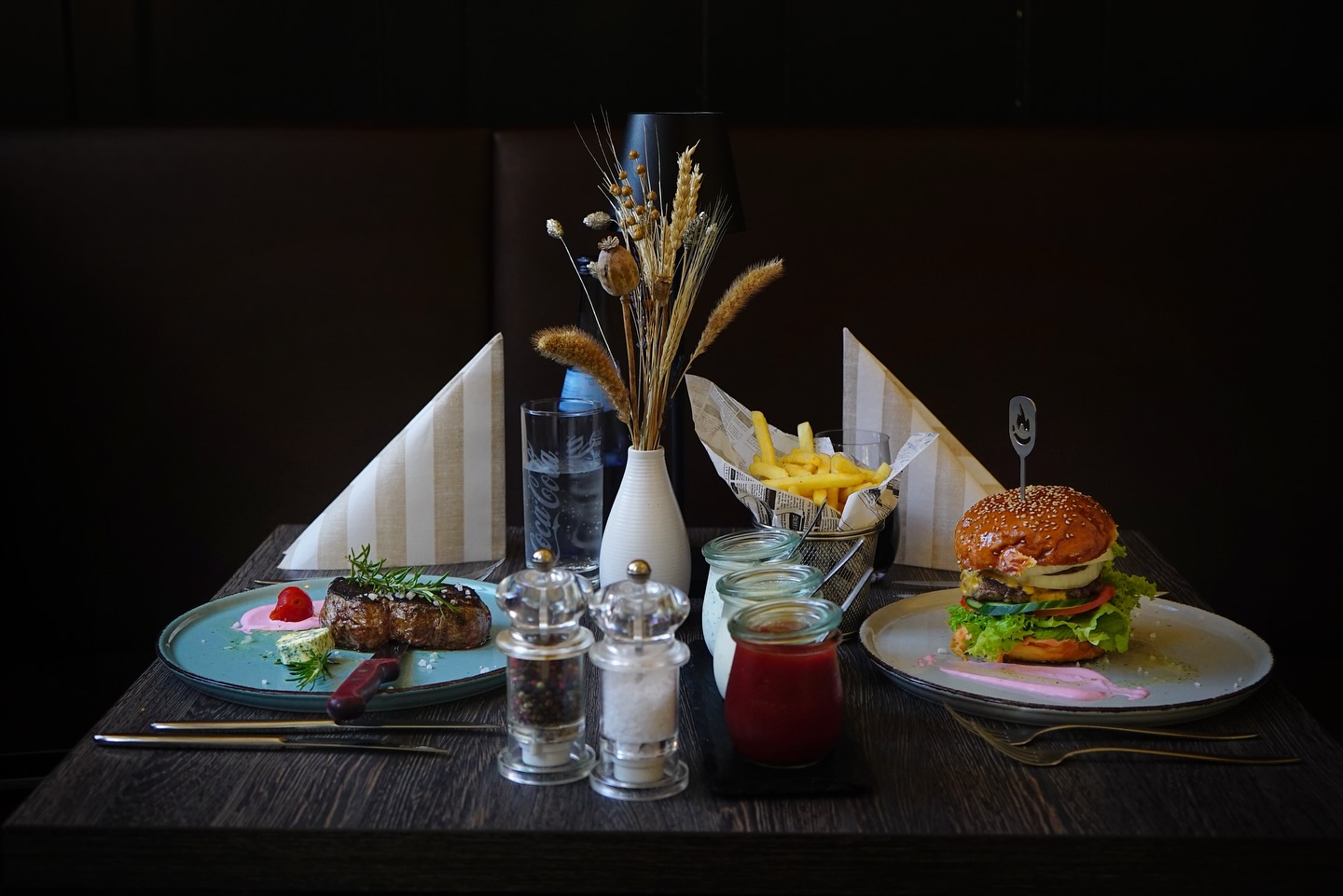 umen" is a good detail for decoration.
"Steak, Burger und Pommes auf einem Tisch mit Trockenblumen im Restaurant moritz Burger 'n Steaks." (