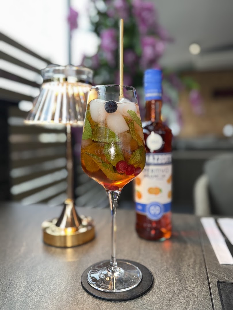 Ein fruchtiger Cocktail mit Minze und Beeren im Trós Montérna bei gemütlicher Tischbeleuchtung.